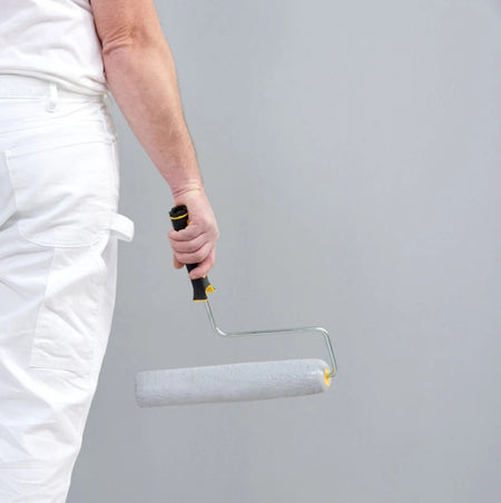 Man holding the Purdy Golden Eagle Roller cover on a purdy roller frame covered with paint.