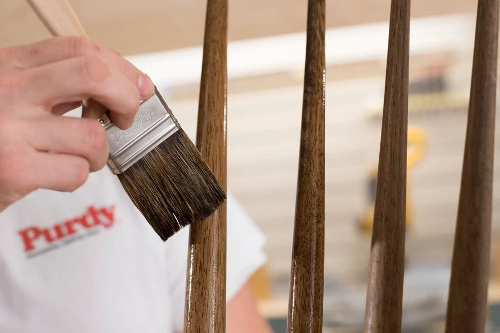 Person using a the Purdy Ox-O Thin paintbrush on wooden spindles of a chair.