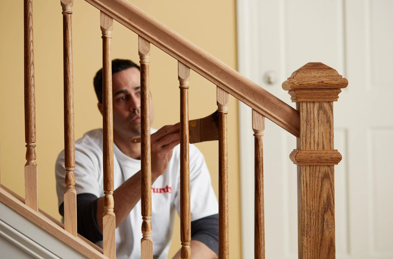 Man painting stair rail spindles with the Purdy Syntox Angular Paint Brush.