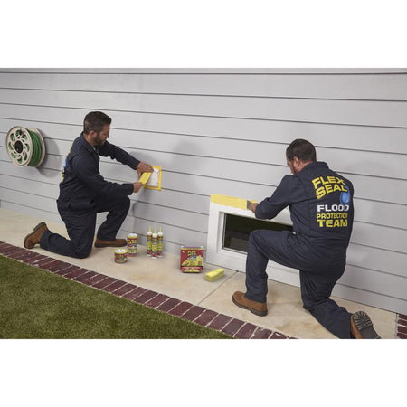 Flex Seal Flood Protection Waterproof Rubberized Tape being applied around the outside of basement windows.
