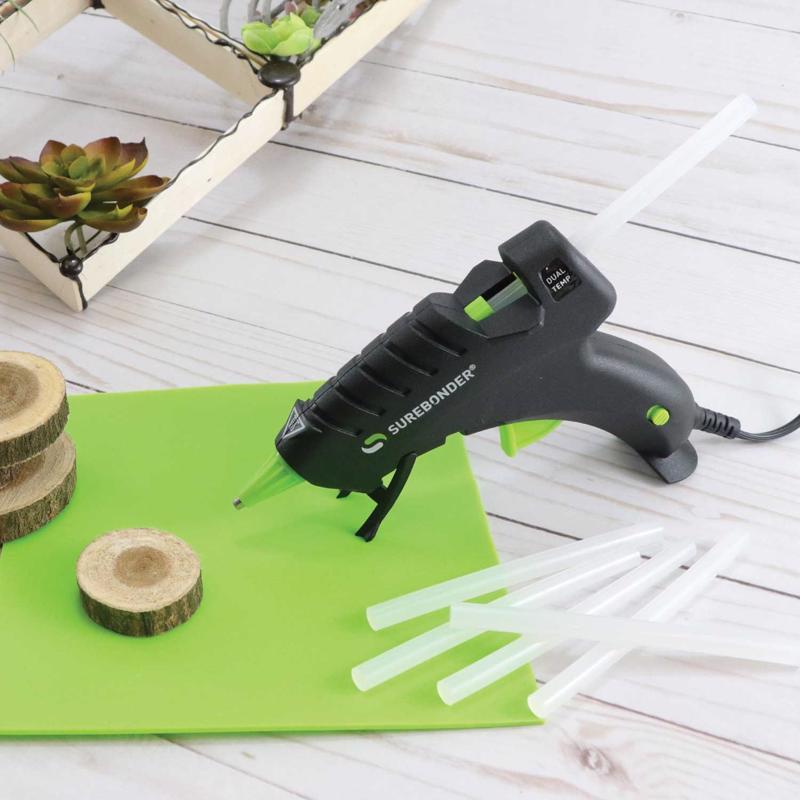 Surebonder Plus Dual Temp Mini Glue Gun Kit shown on its stand with glue sticks next to it.