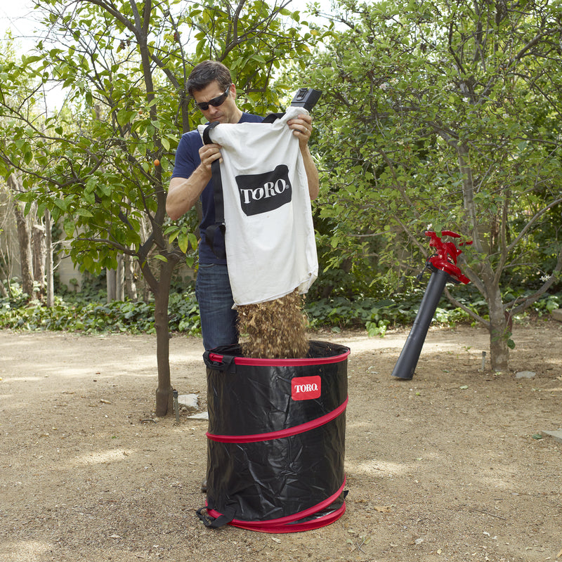 Man dumping mulched leaves into the Toro Spring Bucket 29210