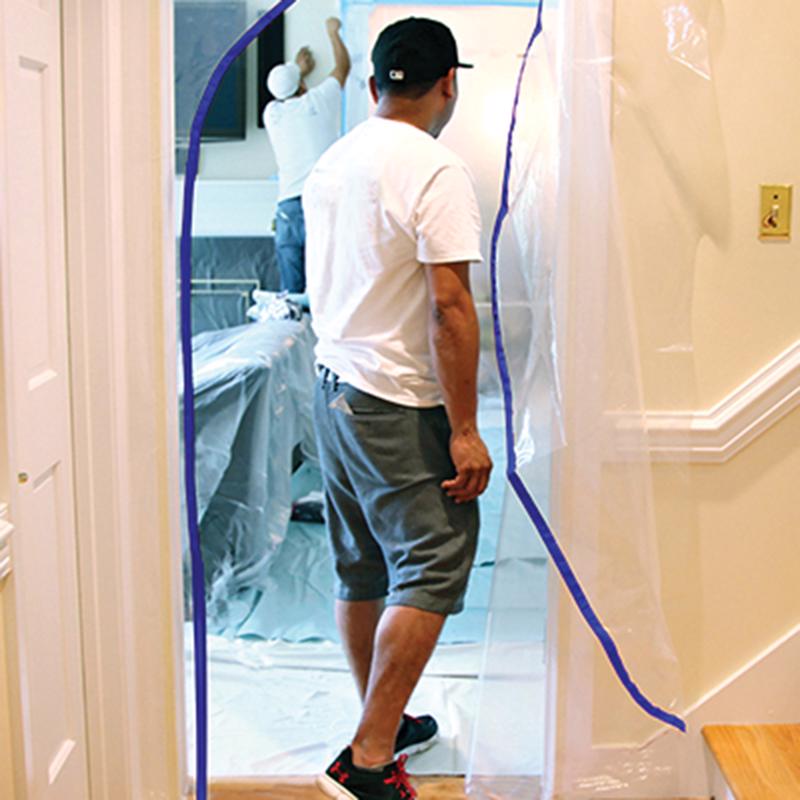 Trimaco E-Z Up Dust Containment Door Kit hung on a doorway with a man walking thru.