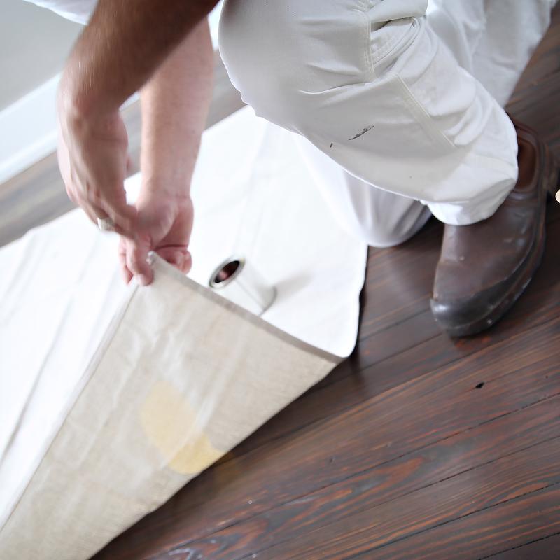 Trimaco Stay Put Canvas Drop Cloth being placed on a hardwood floor