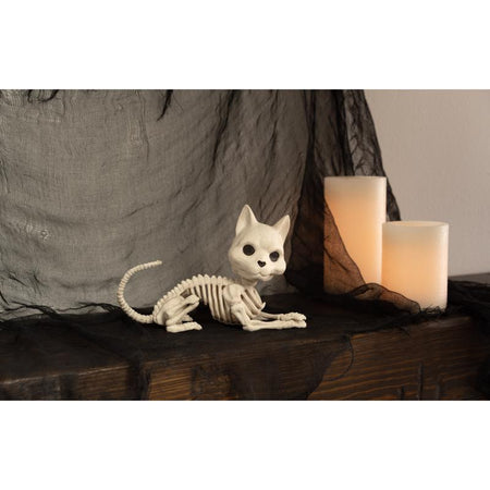 Halloween Skeletal cat figurine on a dark surface with a candle in the background