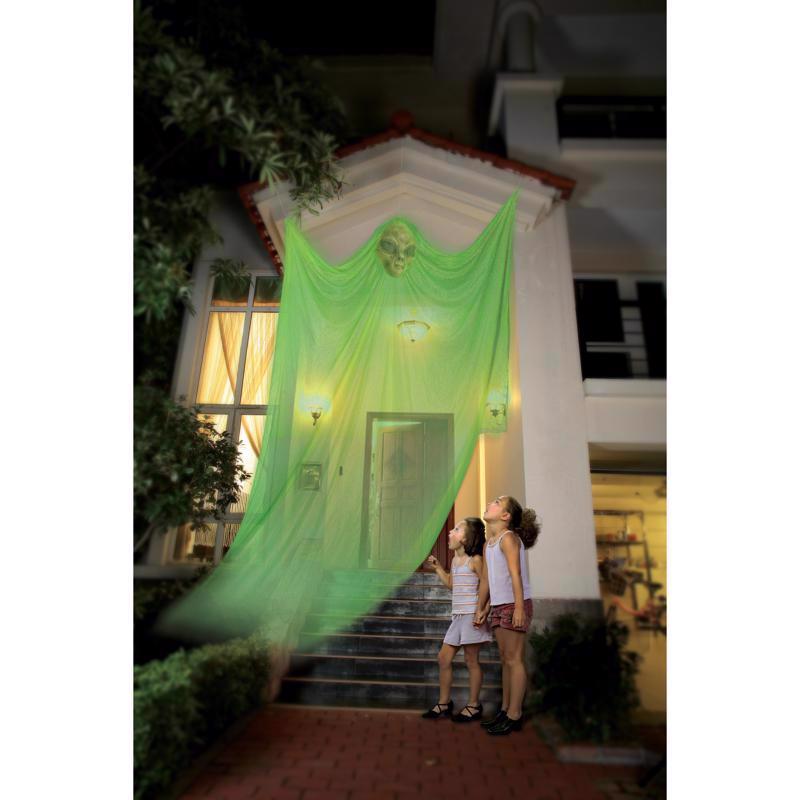 Two children standing on a staircase in front of a building with a glowing green alien.