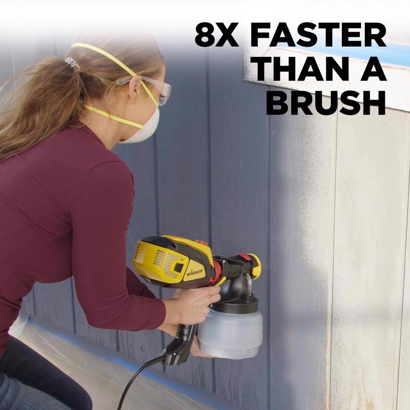 Woman spraying the exterior of a home with a paint sprayer.